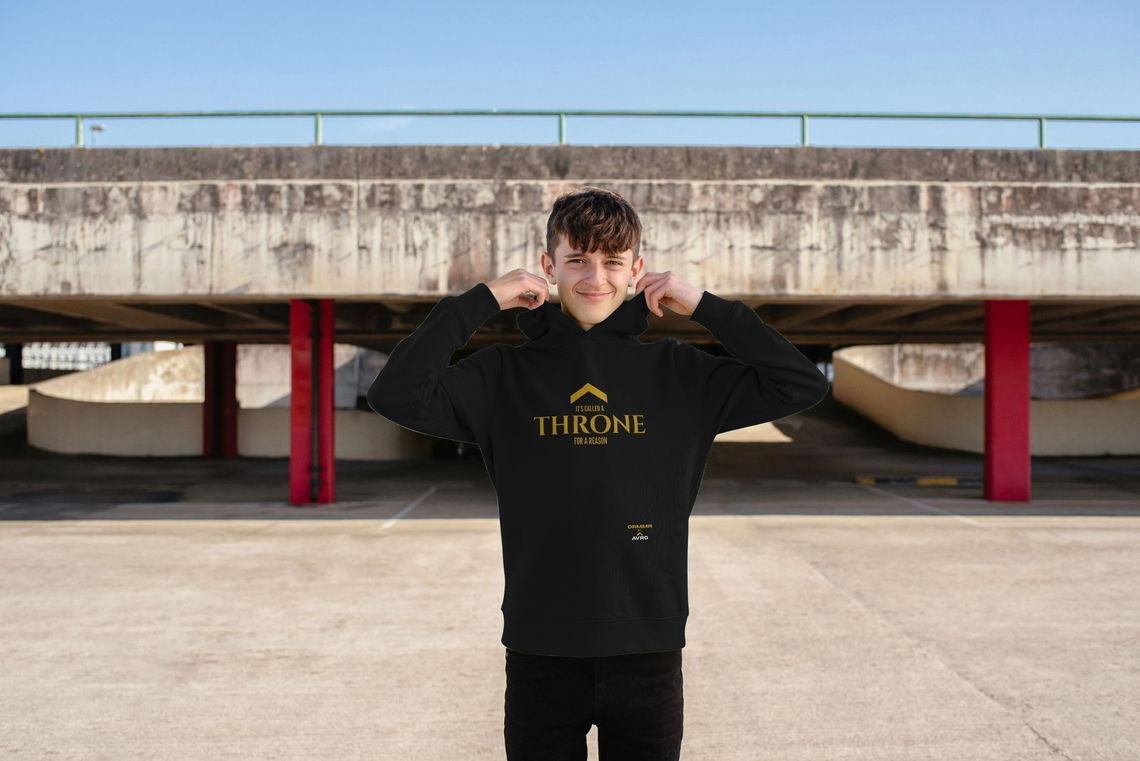 child wearing a black sustainable hoodie from the drummer range from Above Average Clothing. The slogan reads 'it's called a THRONE for a reason' child wearing a black sustainable hoodie from the drummer range from Above Average Clothing. The slogan reads 'it's called a THRONE for a reason'