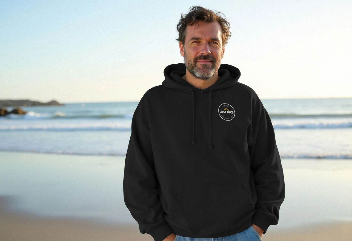 a man on the beach wearing a black sustainable hoodie from Above Average Clothing