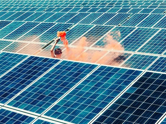 Man stood by solar panels with red smoke canon. One of the renewable energy sources that powers our circular supply chain.